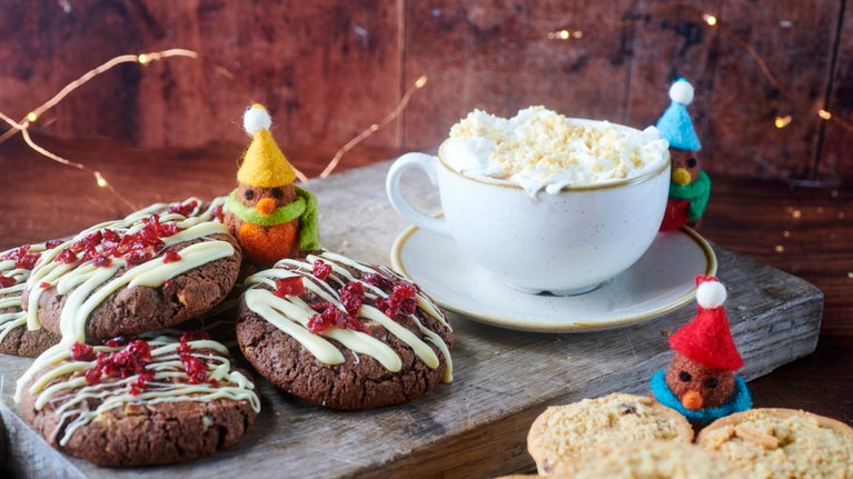 An assortment of cookies and mince pies are displayed on a board.